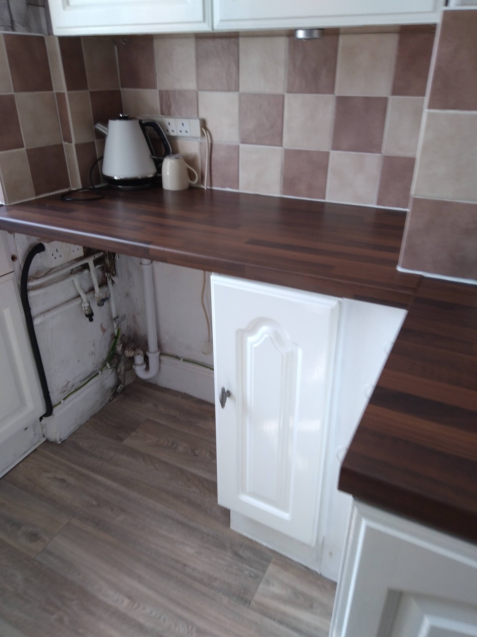 A kitchen worktop, wall tiles and white cupboard after cleaning